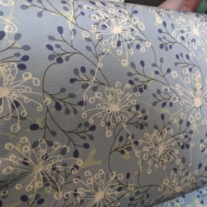 May include: Blue fabric with a white floral pattern. The flowers are stylized and resemble dandelions.