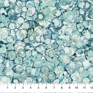 May include: A fabric with a repeating pattern of blue, teal, and white circles with gold accents. The circles vary in size and overlap, creating a textured appearance. A ruler along the bottom measures up to 12 inches.