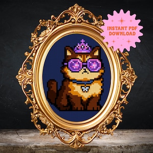 May include: A cross-stitch design of a cat wearing purple sunglasses and a tiara, set against a dark blue background. The cat is framed in an ornate gold oval frame. A pink starburst graphic reads "INSTANT PDF DOWNLOAD".