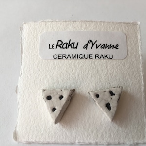 Può includere: Un paio di orecchini triangolari in ceramica bianca con macchie nere. Gli orecchini sono su una carta bianca con il testo "Le Raku d'Yvonne CERAMIQUE RAKU".