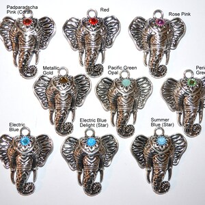 May include: A collection of silver-toned elephant charms, each with a different colored gemstone embedded in the forehead. Gemstone colors include red, pink, green, blue, and gold. Text labels identify each color.
