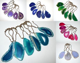Puede incluir: Una colección de ganchos para cortina de ducha con rodajas de ágata pulidas e irregulares en varios colores, incluyendo morado, azul, verde, rosa y blanco. Cada rodaja de piedra natural está unida a un gancho de metal plateado con cadena.