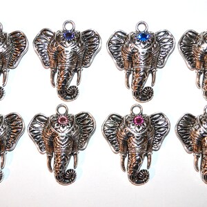 May include: Eight silver-toned elephant pendants with varying colored gemstone accents. Each pendant features detailed trunk and ear designs, and a loop for attaching to a necklace or bracelet. Gemstone colors include purple, blue, orange, and red.