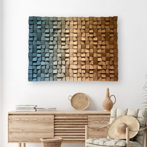 May include: A large, rectangular wooden wall art piece with a gradient color scheme, transitioning from blue to tan. The artwork is composed of numerous small, square wooden blocks. The room features a wooden cabinet, chair, and decorative items.