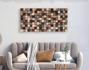 Op de afbeelding: Een grijze bank met een wit plaid en bruine kussens staat voor een muur met een houten wandkunstwerk gemaakt van verschillende gekleurde vierkanten.