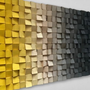 Puede incluir: Una pieza de arte de pared hecha de bloques de madera en un degradado de amarillo, beige, gris y negro.