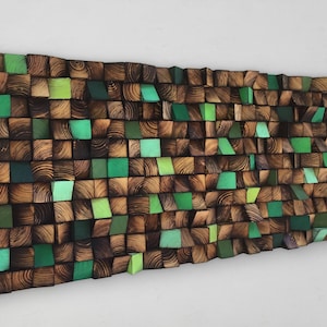 May include: A wall art piece made of wood blocks in various shades of green and brown. The blocks are arranged in a wave-like pattern, creating a textured and modern look.