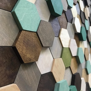 Puede incluir: Una pared cubierta con azulejos hexagonales de madera en varios tonos de marrón, verde y blanco. Los azulejos están dispuestos en un patrón geométrico.
