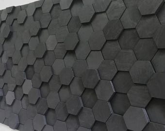 May include: A wall covered in black hexagonal tiles, creating a geometric pattern. The tiles are arranged in a staggered pattern, with some tiles overlapping others.