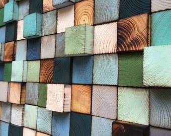 May include: A wall art piece made of wood blocks in various shades of blue, green, brown, and white. The blocks are arranged in a staggered pattern, creating a three-dimensional effect.