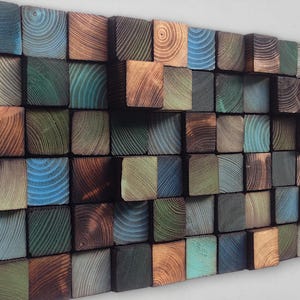 May include: A wall art piece made of wood blocks in various shades of brown, green, and blue. The blocks are arranged in a wave pattern, creating a textured and modern look.