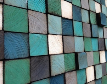 Könnte beinhalten: Ein Wandkunstwerk aus Holzquadraten in verschiedenen Blautönen, Grüntönen und Weiß. Die Quadrate sind in einem versetzten Muster angeordnet, wodurch ein strukturiertes und optisch ansprechendes Design entsteht.