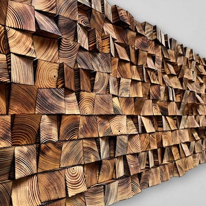 Puede incluir: Una gran pieza de arte mural texturizada hecha de bloques de madera de varios tamaños. Los bloques están dispuestos en un patrón de mosaico, creando un efecto tridimensional. La madera tiene un tono cálido y natural con vetas visibles.