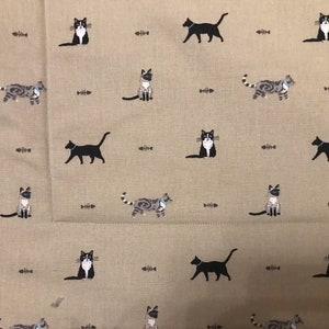 May include: A beige fabric with a repeating pattern of black and grey cats and fish bones. The cats are in various poses, including sitting, standing, and walking.