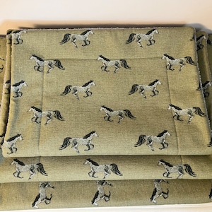 May include: Three green and brown rectangular pet beds with a horse pattern. The beds are stacked on top of each other.