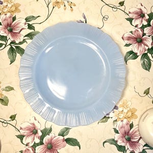 Puede incluir: Un plato de cena de vidrio azul claro con un borde festoneado y una textura ondulada.