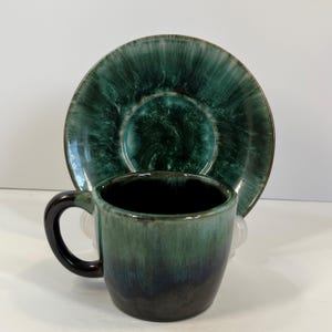 以下が含まれることがあります： 緑と黒のセラミック製のティーカップとソーサーのセット。カップとソーサーは、緑と黒の色の斑点のある釉薬がかかっています。
