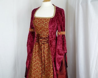 May include: A long, burgundy velvet gown with gold embroidery. The gown has a square neckline and long sleeves with gold trim. The skirt is full and flowing.