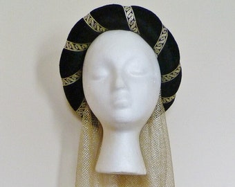 May include: A black velvet headband with gold trim and a matching gold mesh veil. The headband is padded and has a rounded shape.
