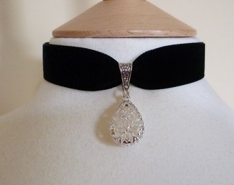May include: A black velvet choker necklace with a silver pendant featuring a floral design.