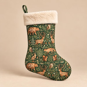 Peut inclure: Une chaussette de Noël en tissu vert foncé avec un motif répétitif d'ours bruns, de cerfs, de renards, d'écureuils et de hiboux parmi de petites fleurs blanches et un feuillage vert. Le revers supérieur est en fausse fourrure crème épaisse.