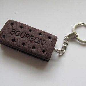 May include: A brown chocolate biscuit keychain with the word "BOURBON" embossed on it. The keychain is attached to a silver metal ring and chain.