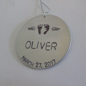Può includere: Ciondolo d'argento con il nome Oliver, la data 27 marzo 2017 e due impronte di piedi con ali d'angelo.