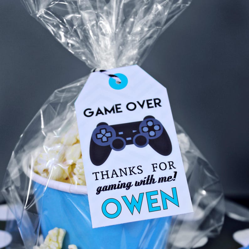 May include: A white favor tag with black text that reads "Game Over" and a black video game controller graphic. The tag also includes the text "Thanks for gaming with me! Owen" in blue text.