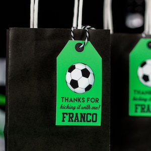 Puede incluir: Bolsa de regalo de f&uacute;tbol verde y negra con una etiqueta que dice "Gracias por patear conmigo! Franco".