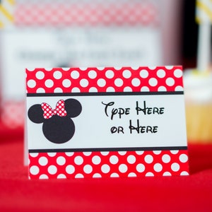 Peut inclure: Une carte blanche avec des pois rouges et une t&ecirc;te de Minnie Mouse noire avec un n&oelig;ud rouge. La carte dit "Type Here or Here".