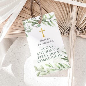 Puede incluir: Una tarjeta blanca con follaje verde y una cruz dorada. El texto en la tarjeta dice "Gracias por celebrar la Primera Comuni&oacute;n de Lucas Anthony".