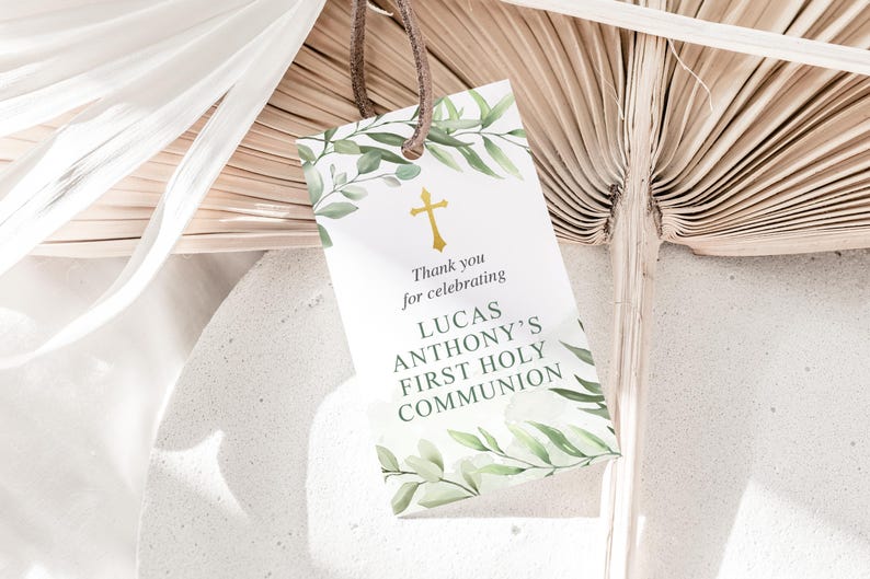 Puede incluir: Una tarjeta blanca con follaje verde y una cruz dorada. El texto en la tarjeta dice "Gracias por celebrar la Primera Comuni&oacute;n de Lucas Anthony".
