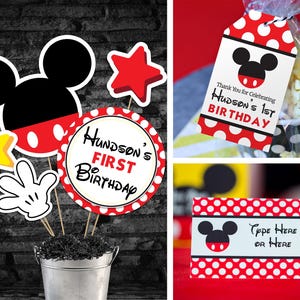 May include: A collection of Mickey Mouse-themed birthday decorations. Includes cutouts of Mickey's head, a hand, stars, and a circle with the text "Hudson's 1st Birthday." Also shown are gift tags and a place card with the same theme.