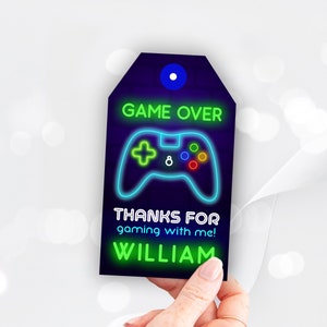 May include: A neon green and blue game over thank you tag with a neon green video game controller and the text "GAME OVER" and "THANKS FOR gaming with me! WILLIAM".