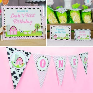May include: A pink and white farm-themed birthday party banner with the word "ONE" in pink letters on each flag. The flags are decorated with black and white cow print and pink and white gingham.