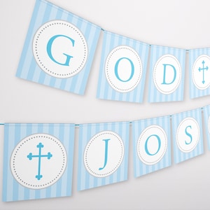Puede incluir: Una pancarta azul y blanca con las palabras "GOD BLESS" y una cruz azul. La pancarta está hecha de papel y tiene un patrón a rayas.