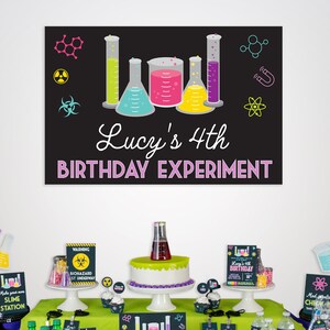 May include: A science-themed birthday party table setting with a black chalkboard sign that reads "Lucy's 4th Birthday Experiment". The table is decorated with beakers, test tubes, and other science-themed decorations. There is a green and white cake with a beaker on top, and a variety of other treats and drinks.