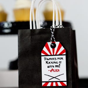 May include: Black and white favor bag with a red and white tag that says "Thanks for kicking it with me! -Alex".