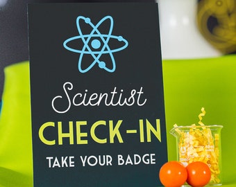 May include: Black sign with a blue atom symbol and the text "Scientist Check-In Take Your Badge".