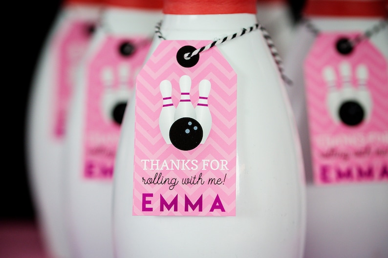 May include: Pink and white favor bags with a pink tag that says "Thanks for rolling with me! Emma". The tag has a black and white bowling pin and ball design.