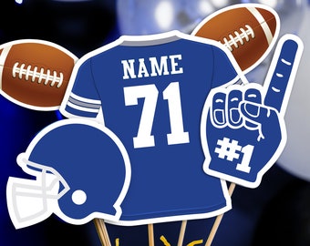 Puede incluir: Centro de mesa de temática futbolística azul y blanco con una camiseta, un balón de fútbol, un casco y un dedo de espuma. La camiseta tiene el número 71 y las palabras "NAME" en ella. El dedo de espuma tiene el número 1.