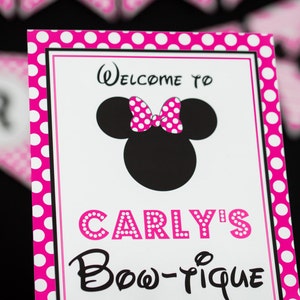 Puede incluir: Un cartel rosa y blanco con lunares con una silueta negra de Mickey Mouse que lleva un lazo rosa con lunares. El cartel dice "Bienvenido a Carly's Bow-tique".