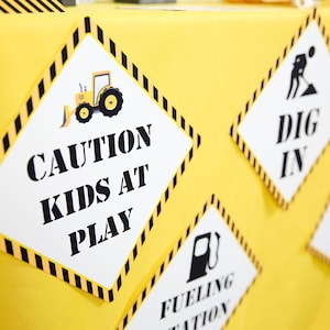 May include: Yellow and black construction themed party signs with the text "Caution Kids at Play", "Dig In", and "Fueling Station".