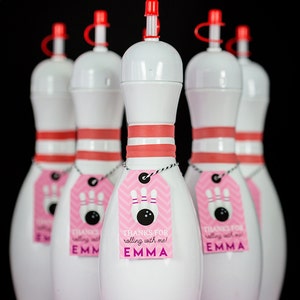 May include: Five white bowling pin shaped bottles with red lids and pink and white chevron patterned tags that say "Thanks for rolling with me! Emma".