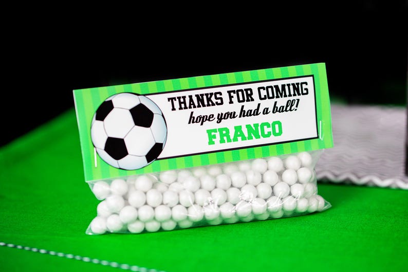 May include: A green and white favor bag with a soccer ball design and the text "Thanks for coming hope you had a ball! Franco". The bag is filled with white candy.