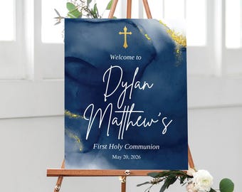 May include: A navy blue sign with gold accents and a gold cross. The sign reads "Welcome to Dylan Matthew's First Holy Communion May 20, 2026" in white script. The sign is displayed on a wooden easel.