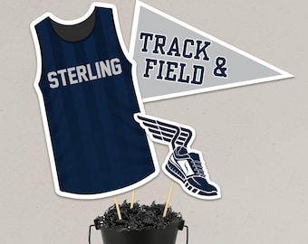 May include: Navy blue track and field decorations. Includes a jersey with "STERLING" text, a pennant with "TRACK FIELD &" text, and a running shoe with wings. The decorations are placed in a black bucket.