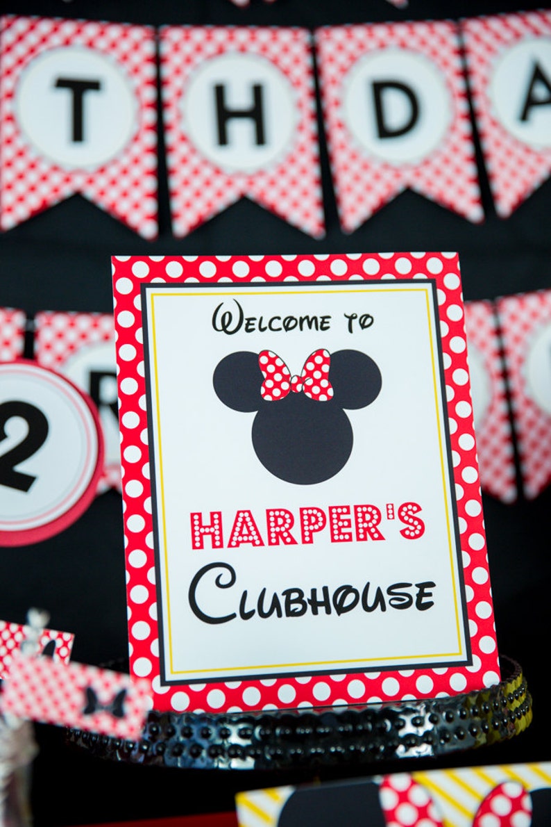 以下が含まれることがあります： 赤と白のドット柄の縁取りと「Welcome to Harper's Clubhouse」の文字が入ったパーティーサイン。ミッキーマウスの頭の黒いシルエットと赤い水玉模様のリボンが特徴です。「THDA」という文字が入ったバナーが背景にあります。