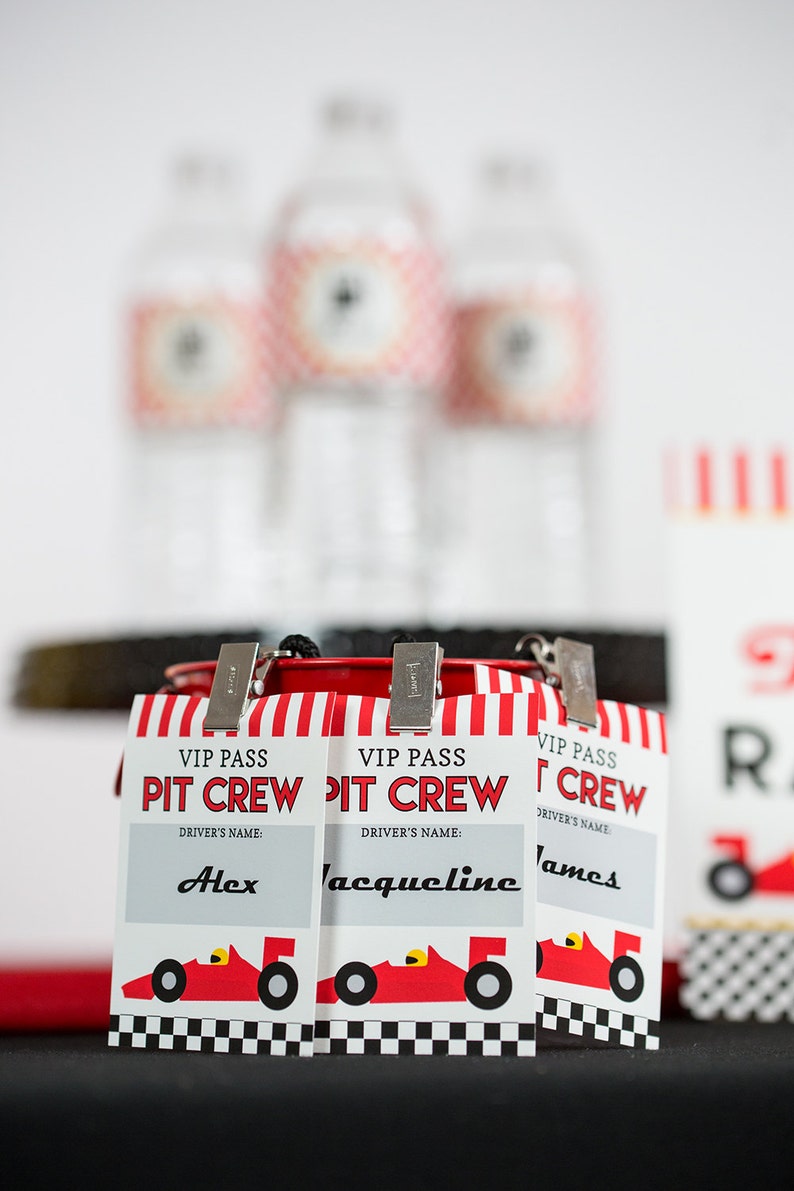 May include: Three red and white striped VIP pass cards with the text "VIP Pass Pit Crew" and a red race car graphic. The cards have a space for a driver's name and the names "Alex", "Jacqueline", and "James" are written in.