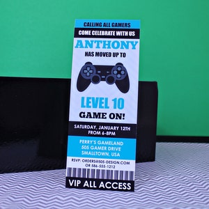 May include: A blue and black invitation with a video game controller graphic. The invitation reads "Calling all gamers, come celebrate with us Anthony has moved up to Level 10 Game On!"  The invitation is for a party on Saturday, 12th January from 6-8pm at Perry's Gameland, 505 Gamer Drive, Smalltown, USA. RSVP: orders@505-design.com or 586-555-1212. VIP All Access.